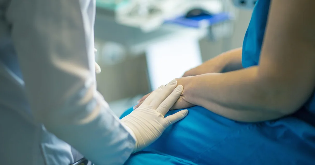 Profissional de saúde segurando a mão de um paciente em consultório