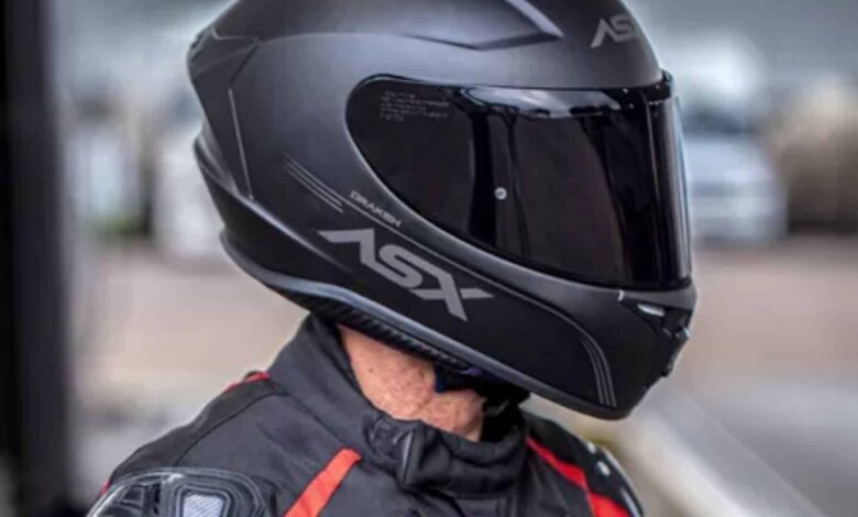 Motociclista com capacete preto e viseira fume.