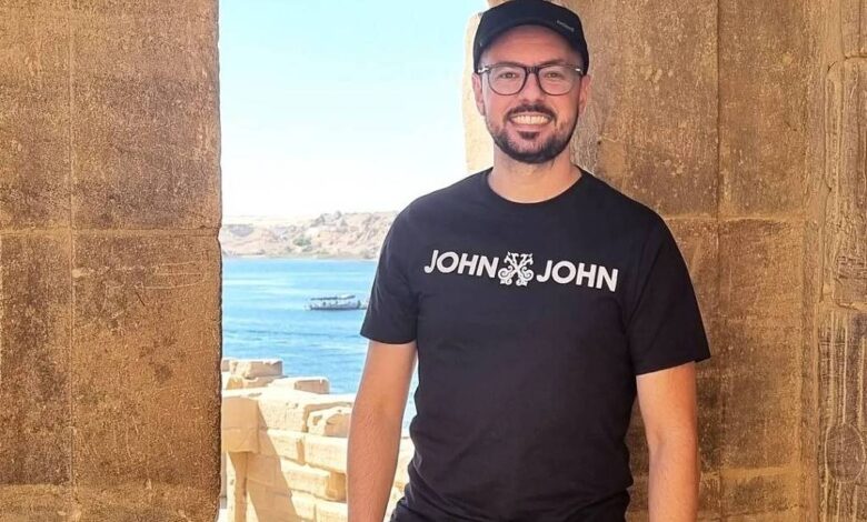 Um homem está posando em uma abertura de pedra, com vista para um corpo d