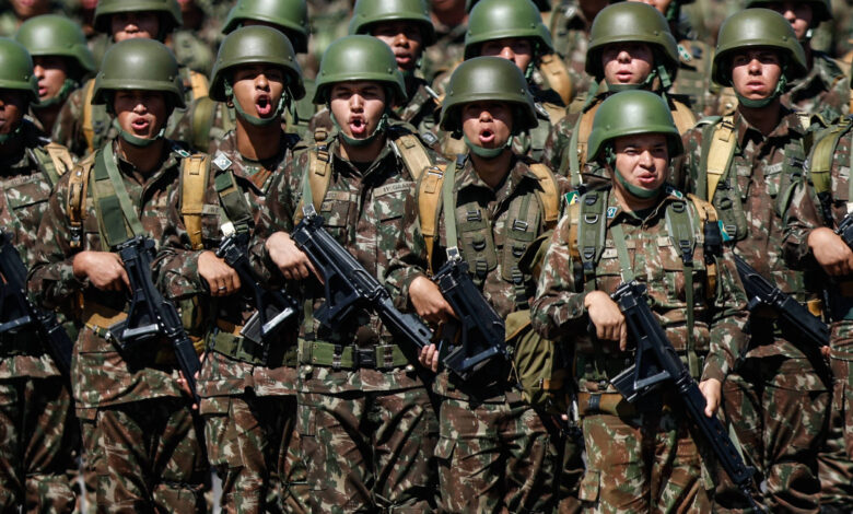 Militares com roupa camulflada marcham e seguram fuzis com as mãos