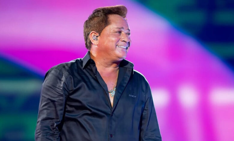 Leonardo no palco, de camisa social preta, olhando para o lado e sorrindo